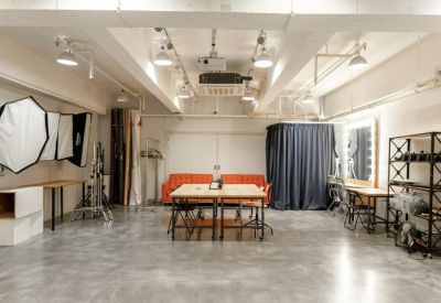 Spacious studio workspace with a large wooden meeting table and professional studio lighting.