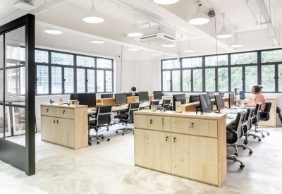 Bright office space with rows of desks and large windows overlooking the city.