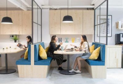 Modern breakout space featuring blue cushioned booths and yellow accent pillows.