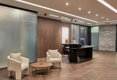 Warm reception area with wood paneling, marble flooring, and stylish lounge chairs.
