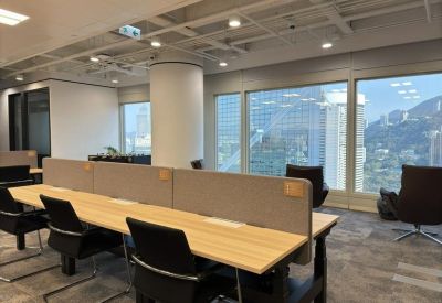 Bright open-plan office with timber-topped desks and city views through large windows.