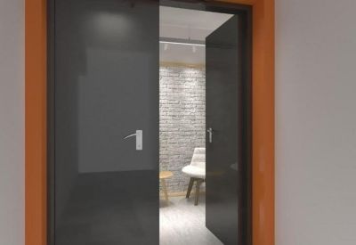 Entrance to a private office suite through dark glass double doors with orange frames.