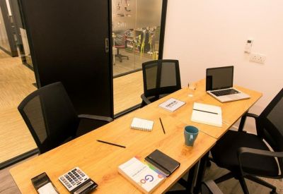 Four-person meeting table with a laptop and documents near a glass door.