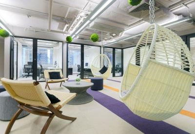 Playful breakout area featuring hanging wicker pod chairs and colorful striped carpeting.