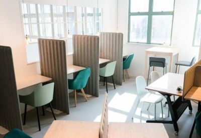 Modern workspace featuring semi-private desk pods and teal velvet chairs by a window.