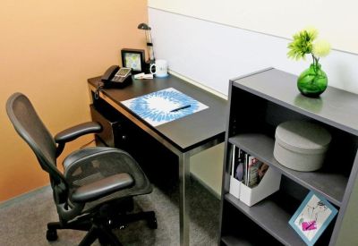 Private office workstation with an ergonomic chair and a small bookshelf.