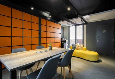 Communal breakout area featuring an orange grid feature wall and a curved yellow sofa.