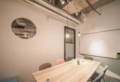 Modern meeting room featuring a wooden table, whiteboard, and industrial-style exposed ceiling.