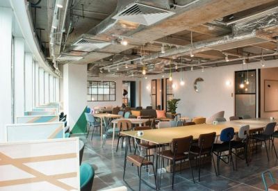 Large open-plan communal workspace with diverse seating options and warm hanging pendant lights.