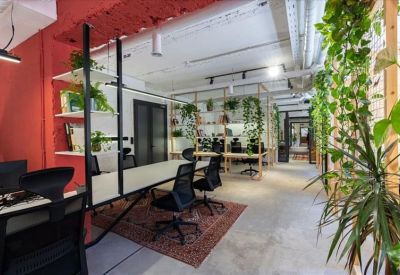 Vibrant coworking space with red walls, indoor plants, and wooden communal tables.