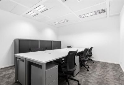 Sleek, minimalist private office suite with long white desks and black ergonomic chairs.