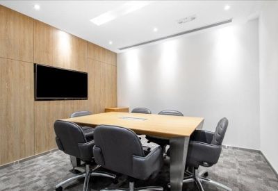 Professional meeting room with a light wood table and comfortable grey executive chairs.