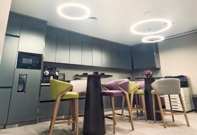 Communal breakout area with circular ceiling lights and colorful bar stools.