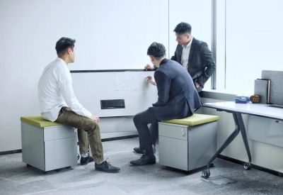 Informal meeting space with three people collaborating around a whiteboard.