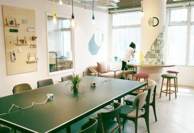 Meeting room with a large black table, colourful stools, and abundant natural light.