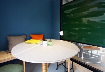 Small meeting nook with a round white table, blue accent wall, and chalkboard.