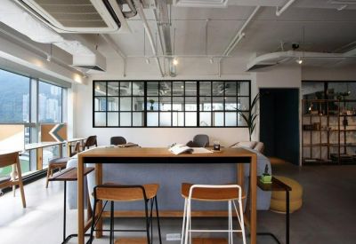 Wide-angle interior showing a large common area with a wooden high table and industrial ceiling.