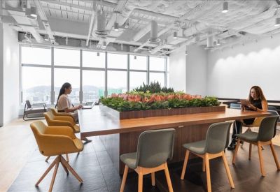 Large wooden communal table with a central planter and ergonomic seating.
