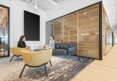 Semi-private meeting nook with a leather sofa and wooden slat partition.