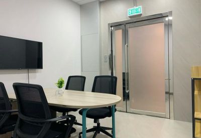 Meeting room with an oval wooden table, black chairs, and a wall-mounted TV.