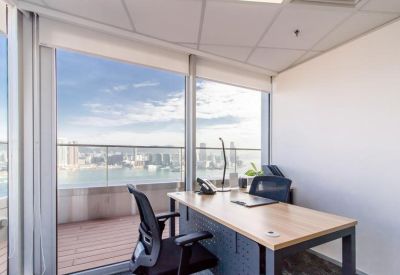 Private office featuring a wooden desk and glass doors opening onto a balcony with harbor views.