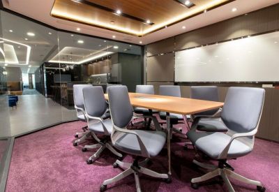 Sophisticated boardroom with a wooden table, grey chairs, and a purple carpet.