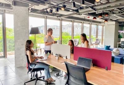 Modern meeting area with team members collaborating at a wooden desk near a large window.