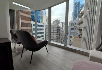 Relaxed breakout area with comfortable lounge chairs overlooking the city skyline through curved windows.
