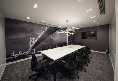 Modern meeting room with a large white table, artistic chandelier, and a black and white bridge mural.