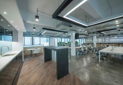 Modern kitchen and breakout area with a dark wood breakfast bar and polished concrete floors.