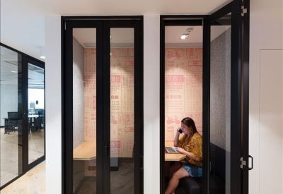 Two private phone booths with glass doors and a person working inside.