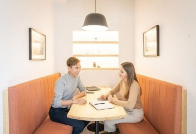 Private meeting booth with orange banquette seating and a round table.