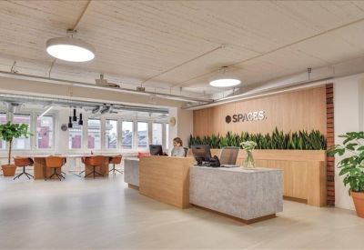 Bright reception area featuring a light wood desk and lush green plant wall.