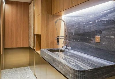 Kitchenette with a marble countertop, high-end faucet, and wooden cabinetry.
