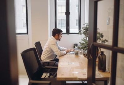 Private office suite featuring a wooden desk and city views through large windows.