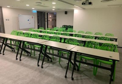 Training room set up with rows of tables and bright green chairs.