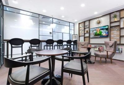 Bright communal lounge with cafe-style seating and wall-mounted television.