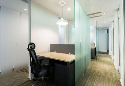 Individual workstation with an ergonomic chair separated by a glass partition.