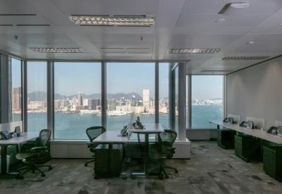 Open-plan workspace with multiple desks and panoramic views of Victoria Harbour.