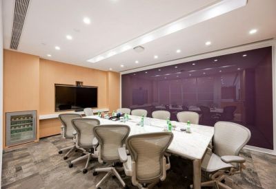 Meeting room with a white marble table, ergonomic chairs, and a purple accent wall.