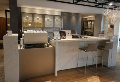 Modern marble reception desk with an espresso machine and high stool seating.
