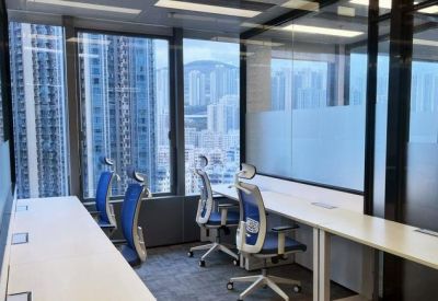 Sun-drenched shared office space with white desks and expansive city views.