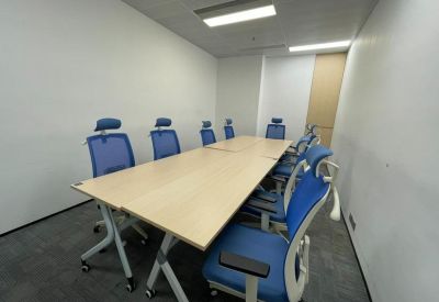 Bright conference room with a light wood table and ergonomic blue chairs.