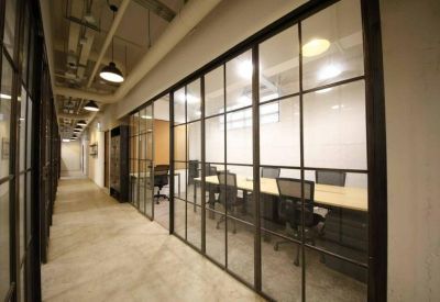 Professional meeting room with a long table and black chairs behind glass walls.
