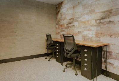 Private office space featuring two workstations and a rustic wood-plank feature wall.