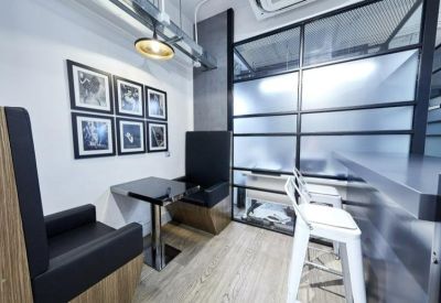 Communal breakout area with booth seating, bar stools, and framed wall art.