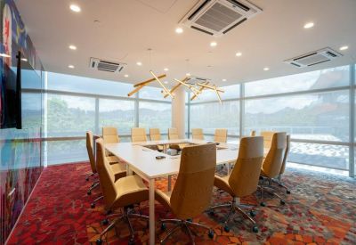 Bright conference room with a large white table, tan chairs, and floor-to-ceiling windows.