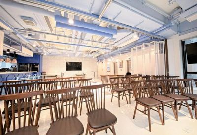 Large meeting room arranged with rows of wooden chairs and a presentation screen.