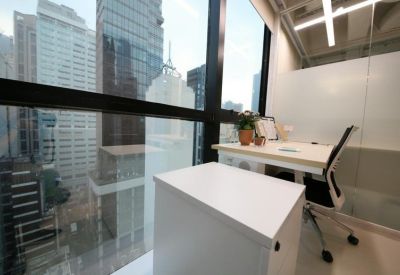 Bright corner office with city views, a white desk, and natural light.