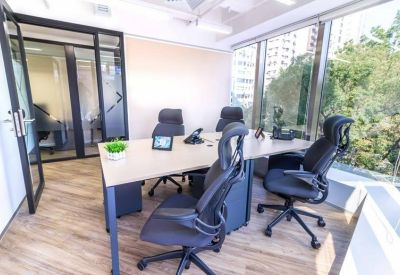 Private glass-walled office with wooden floors and city views.